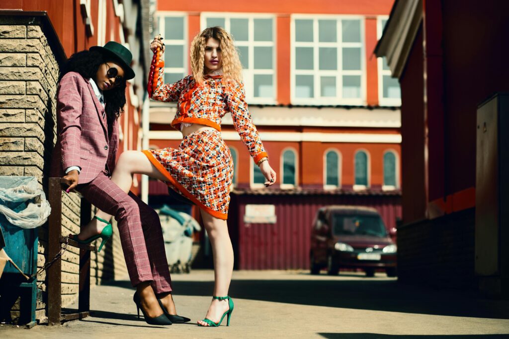 Stylish women posing in an urban alley showcasing contemporary fashion trends.